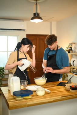 Önlüklü genç çift sıcak bir mutfakta krep hamuru hazırlıyorlar..