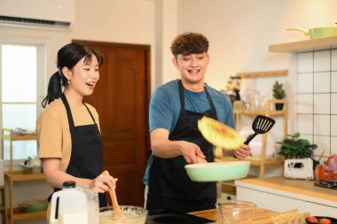 Ortağı izlerken ve gülerken adam tavada krep çeviriyor..