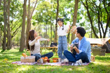 Neşeli aile dışarıda kamp kuruyor, abur cuburları paylaşıyor ve parkta çadırın yanında kaliteli zaman geçiriyor...