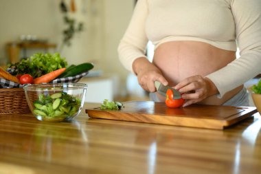 Hamile kadın mutfakta taze sebze salatası hazırlıyor..