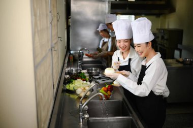 Gülümseyen genç aşçılar profesyonel bir aşçılık okulunda mutfak hijyeni ve takım çalışması öğreniyor..