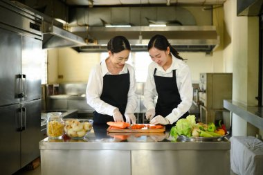 Aşçılık hocası bir öğrenciye pratik bir yemek kursunda havuç dilimleme konusunda rehberlik ediyor..