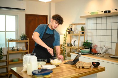 Sıradan bir ev yemeği sırasında beyaz bir adam krep için hamur işi çırpıyor..