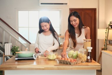 Genç Asyalı kız, annesiyle sıcak bir evde yemek yapmayı öğreniyor..