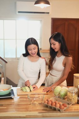 Genç Asyalı kız, annesiyle sıcak bir evde yemek yapmayı öğreniyor..