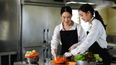 Profesyonel bir mutfakta aşçılık kursunda sebze hazırlayan iki kız öğrenci..