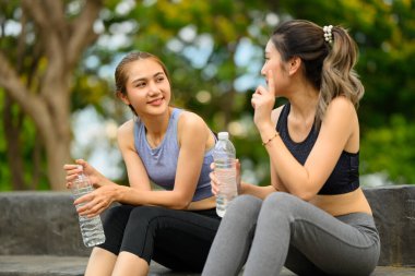 Kadın arkadaşlar egzersizden sonra serinliyor, sohbetin ve açık havada su içmenin keyfini çıkarıyorlar..