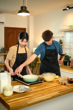 Önlüklü kadın ve erkek sıcak ev mutfağında krep yapmaya başlıyorlar..