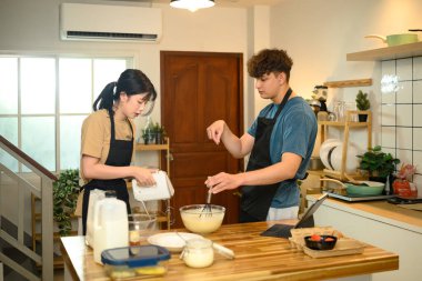 Genç çift sıcak mutfakta krep malzemeleri hazırlıyor..