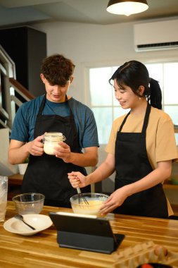 Genç çift sıcak mutfakta krep malzemeleri hazırlıyor..