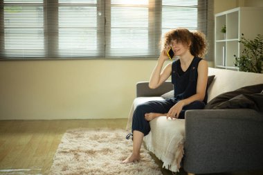Rahat bir kadın, rahat bir oturma odasında telefon konuşmasının keyfini çıkarıyor..