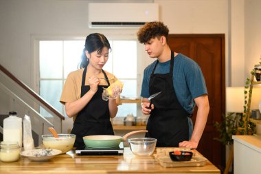 Önlüklü kadın ve erkek sıcak ev mutfağında krep yapmaya başlıyorlar..