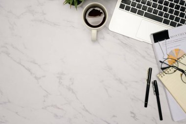 Kahve, dizüstü bilgisayar, not defteri ve mali raporlu minimalist ofis masasının üst görünümü.