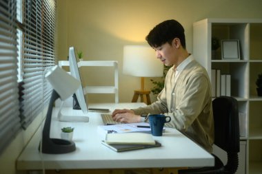 Parlak, modern bir masada çalışan gülümseyen genç adam..