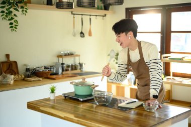 İnsan yemek pişirirken mikrofon gibi kaşıkla şarkı söyler...