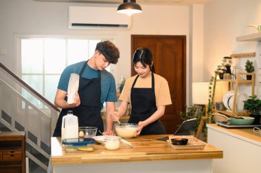 Neşeli genç çift mutfakta krep hamuru hazırlıyor..