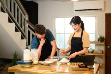 Neşeli genç çift mutfakta krep hamuru hazırlıyor..