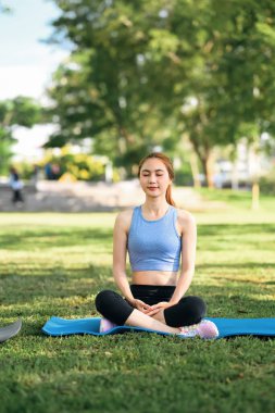Kadın meditasyon yapıyor ve yoga minderinde derin nefes alıyor..