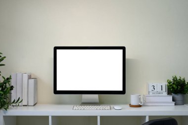 Masaüstü monitörü takvime bağlı beyaz masada olan minimal ev ofisi.