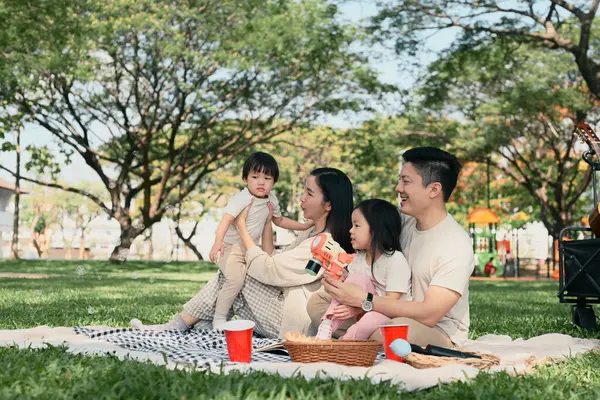 Neşeli aile, güneşli bir parkta baloncuklarla oynayarak kaliteli zaman geçiriyor..