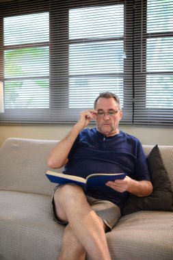 Oturma odasında konsantrasyonlu rahatlamış yetişkin kitapları..