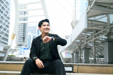 Genç girişimci zamanı kontrol ediyor, finans bölgesinde randevu bekliyor..