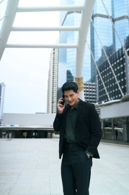 Modern bir şehirde yürürken telefonda konuşan zeki bir işadamı..