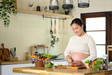 Mutlu hamile kadın evde sağlıklı bir salata hazırlıyor..