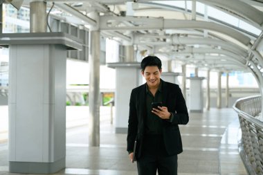 Kendine güveni tam bir işadamı modern şehir yolunda akıllı telefon kullanıyor..