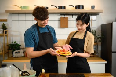 Genç çift gururla üzerinde çilek olan ev yapımı krep tabağını sunar..