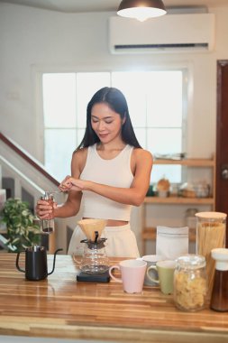 Asyalı kadın kahve hazırlıyor. Tezgahta taze fasulye ve fincanlar var..