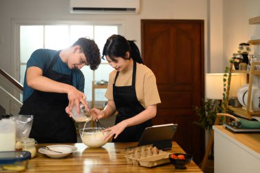 Gülümseyen çift mutfakta krep hamuru hazırlıyor..