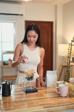 Güzel bir kadın taze kahve demlerken filtreden kahve döküyor..