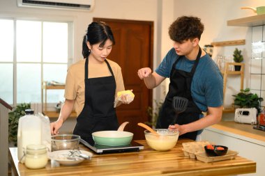 Kadın ve erkek önlük giyip evde krep hazırlıyorlar..