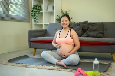 Mutlu hamile kadın antrenman yaparken paspasın üzerinde rahatlıyor..