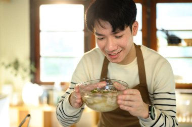 Mutlu Asyalı adam yeni hazırlanmış erişte çorbasını sunar..