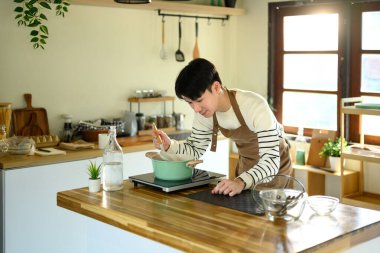 Mutlu Asyalı adam modern bir fırında yemek hazırlıyor..