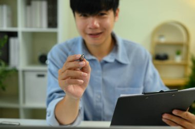 Kameraya doğru kalem uzatan adama yaklaş, imzayı ya da onayı sembolize ediyor..