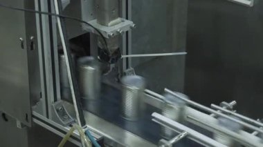 Otomatik gıda konserve üretim tesisinde çalışan yüksek hızlı endüstriyel makinelerin yakın görüntüsü.