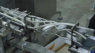 Alüminyum teneke kutular, modern üretim hattındaki eğri bir taşıma sisteminden hızla geçerler..