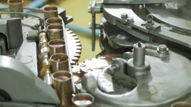 Balık konservesi fabrikasında içi sos dolu konserve kutuları taşıyan endüstriyel makineler..