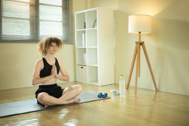 Huzurlu genç bir kadın, parlak bir evde meditasyon yapıyor..