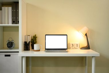 Penceresi perdeli, dizüstü bilgisayarı, defterleri ve kalem tutacağı olan temiz çalışma alanı.