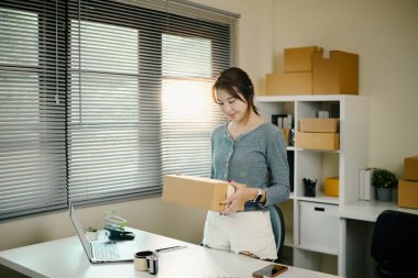 Küçük işletme sahibi ev ofisinde duran paketlenmiş bir paketi teslim ediyor..