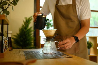 Adam kahve damlatıcısına sıcak su döküyor, sabah rutininin tadını çıkarıyor..