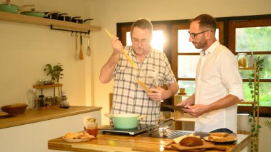 Mutlu baba ve oğul birlikte yemek hazırlıyor ve mutfakta sohbet ediyorlar. Babalar Günü konsepti.