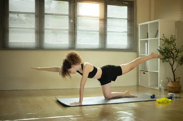 Yoga minderinin üzerinde gerinen bir bayan sporcu. Ev çalışması kavramı.