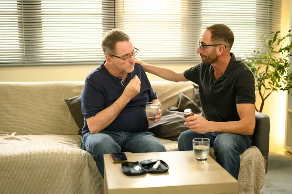 Yaşlı bir adam reçeteli ilaç alırken oğlu tarafından yönlendirilir. Babalar Günü konsepti.