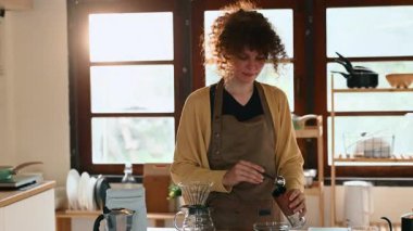 Kahve çekirdeklerini öğütücüye döken mutlu bir genç kadın..