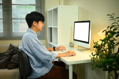 Genç adam rahat bir ofisteki masaüstü bilgisayarında çalışıyor..